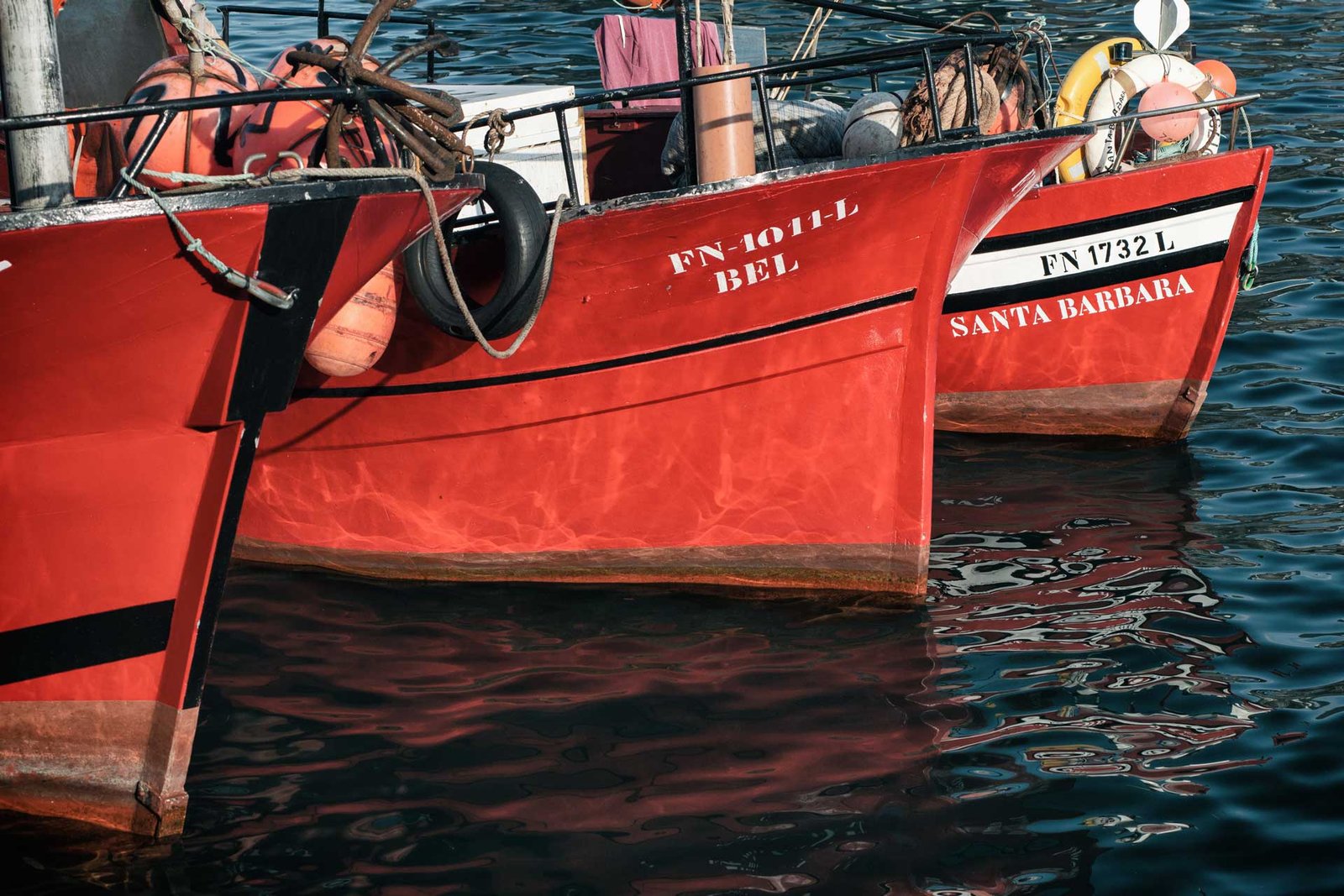 Three red metal fishermen boats in Funchal harbour