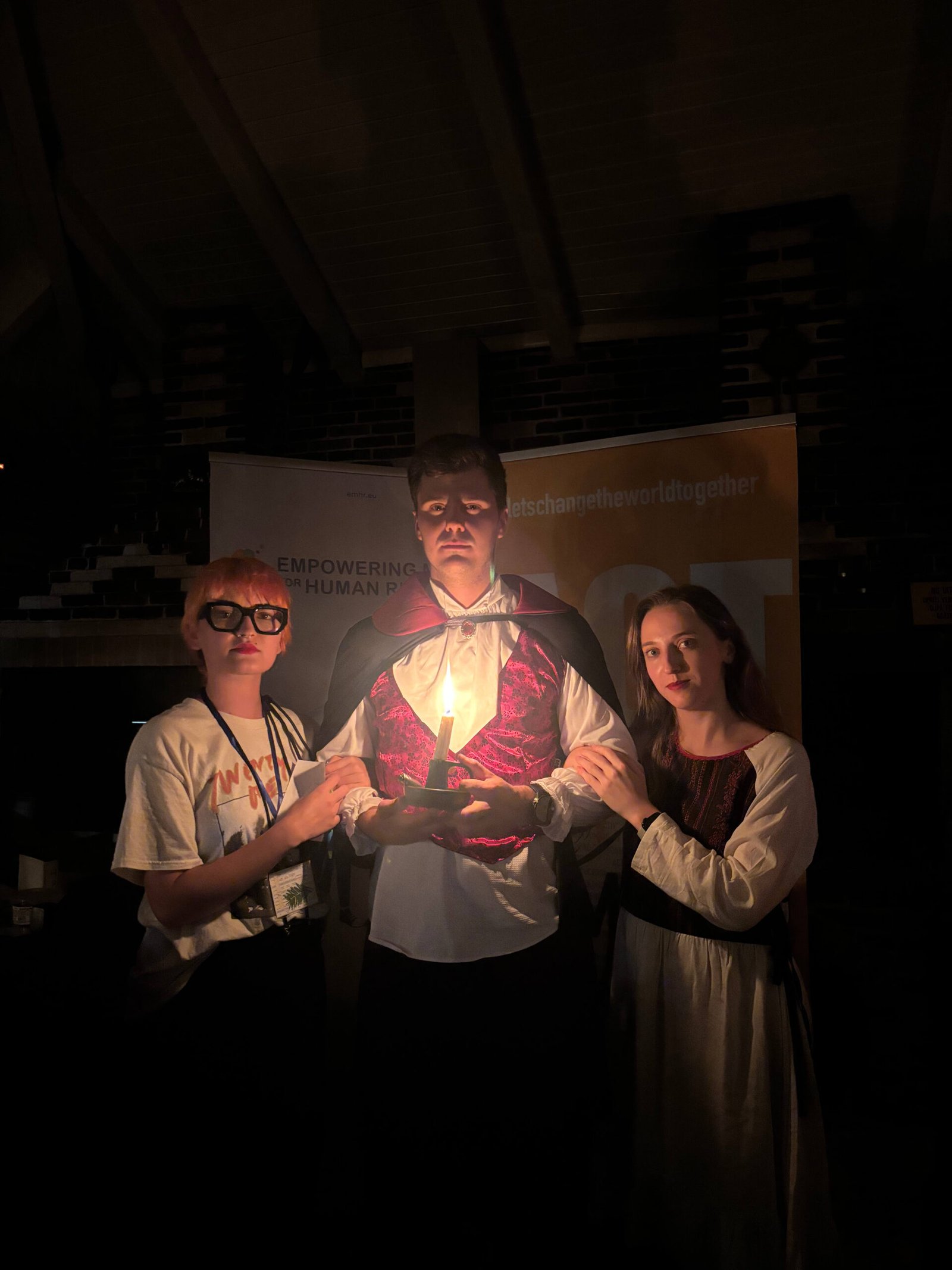 Three people in candlelight in dark room